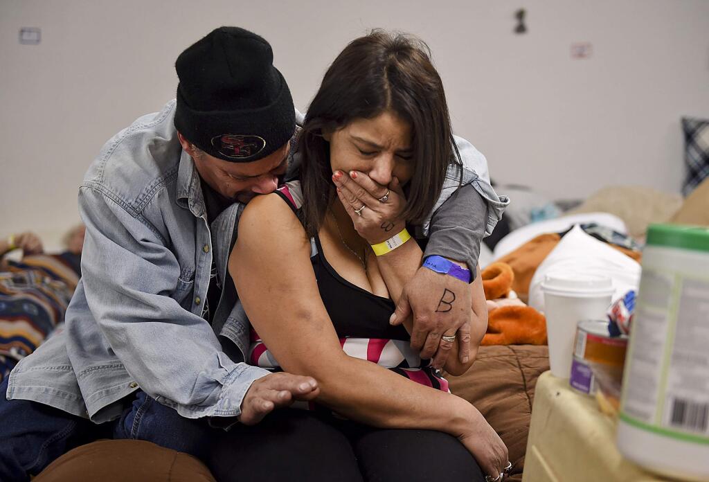 Joseph Grado and his wife, Susan Grado, embrace while staying at a shelter for fire victims at East Avenue Church, Monday, Nov. 12, 2018, in Chico, Calif. They lost their Paradise home in the Camp Fire. The shelter is staffed by a doctor and nurses from Feather River Hospital, who are volunteering despite being fire victims themselves. (Hector Amezcua/The Sacramento Bee via AP)