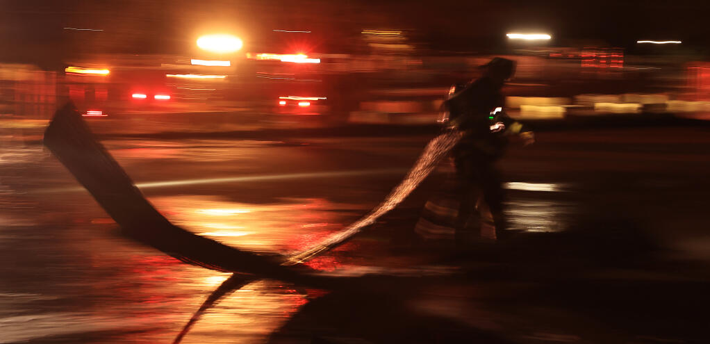A Santa Rosa firefighter pulls corrugated siding from a warehouse that caught fire on Central Avenue in Santa Rosa, early Sunday, Jan. 29, 2023. (Kent Porter/The Press Democrat)