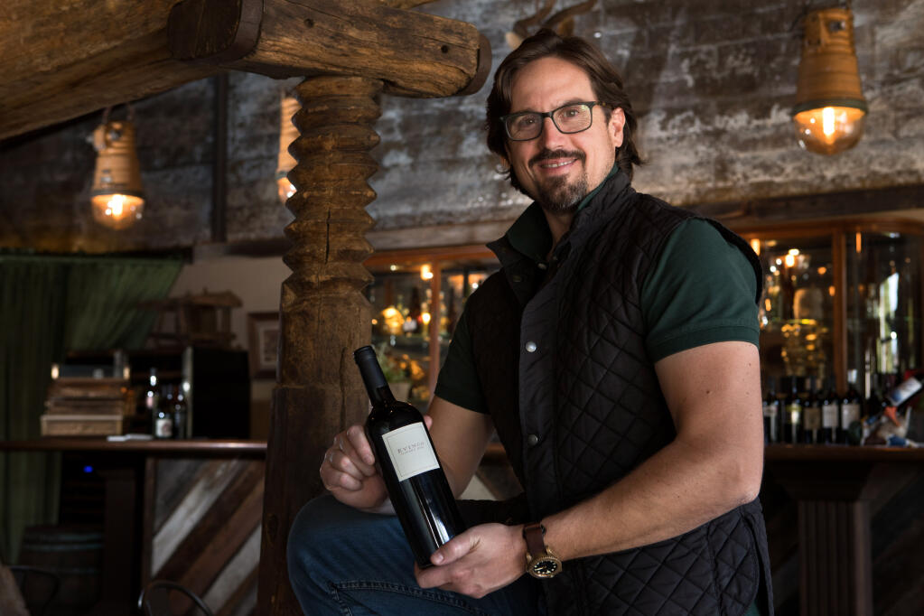 Mario Sculatti, winemaker and co-founder of Evinco Winery DAO, holds a bottle of Evinco Winery DAO, a 2013 Napa Valley Cabernet Sauvignon, in the VAULT wine tasting room, Tuesday, July 26, 2022, in Calistoga. (Darryl Bush / For The Press Democrat)