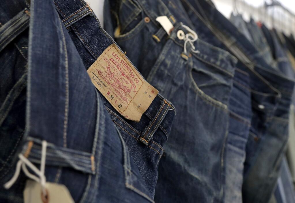 FILE- This Feb. 9, 2018 photo shows Levi's jeans hanging on a wall at Levi's innovation lab in San Francisco. Well-known jeans company Levi Strauss & Co. said Wednesday, Feb. 13, 2019, that it plans to raise about $100 million through an initial public offering. The number of shares to be offered and the price range has yet to be determined. (AP Photo/Jeff Chiu, File)