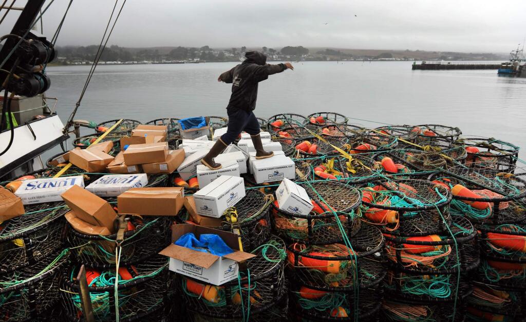 A deck hand with the Verna Jean balances on crab bait as and other crew members head out to sea for the start of crab season, Monday Nov. 13, 2017 in Bodega Bay. (Kent Porter / The Press Democrat) 2017