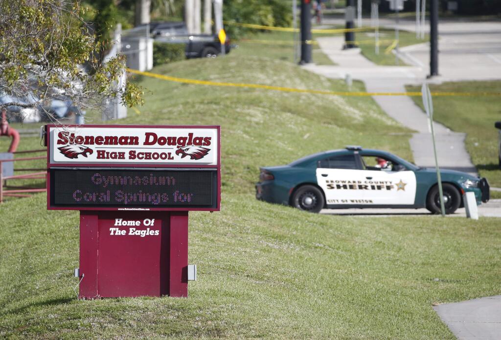 Law enforcement officers block off the entrance to Marjory Stoneman Douglas High School, Thursday, Feb. 15, 2018 in Parkland, Fla. Nikolas Cruz was charged with 17 counts of premeditated murder on Thursday, the day after opening fire with a semi-automatic weapon at the school. (AP Photo/Wilfredo Lee)