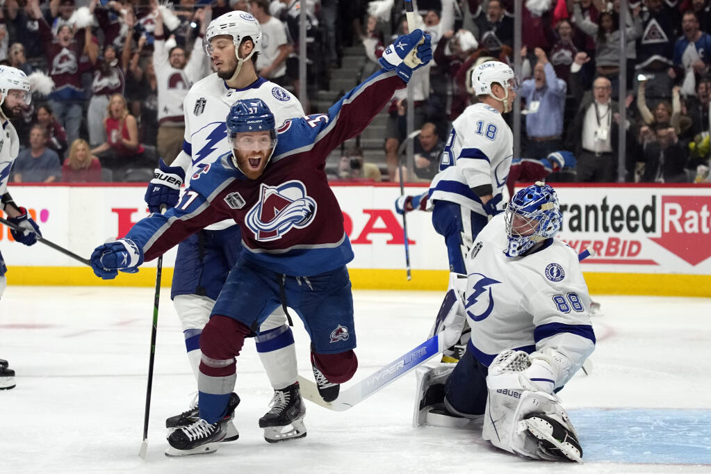 Colorado Avalanche left wing J.T. Compher, left, celebrates next to Tampa Bay Lightning goaltender Andrei Vasilevskiy, right, after an overtime goal by Andre Burakovsky in Game 1 of the Stanley Cup Final on Wednesday, June 15, 2022, in Denver. (AP Photo/John Locher )