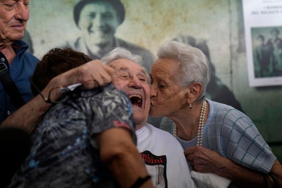Martin Adler, a 97-year-old retired American soldier, center, receives a kiss from Mafalda, right, and Giuliana Naldi, whom he saved during WWII, during a reunion at Bologna's airport, in Italy, Monday, Aug. 23, 2021. For more than seven decades, Adler treasured a black-and-white photo of himself as a young soldier with a broad smile with three impeccably dressed Italian children he is credited with saving as the Nazis retreated northward in 1944. The veteran met the three siblings - now octogenarians themselves - in person for the first time on Monday, eight months after a video reunion.  (AP Photo/Antonio Calanni)