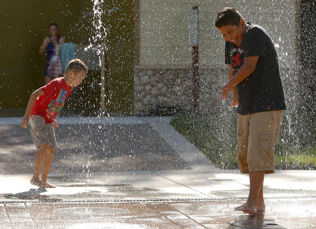 Henry Porras, 9, right, laughs as he gets sprayed with a jet of water in the new splash park at the entrance to the Prince Memorial Greenway in Santa Rosa, California on Thursday, October 6, 2016. (Alvin Jornada / The Press Democrat)