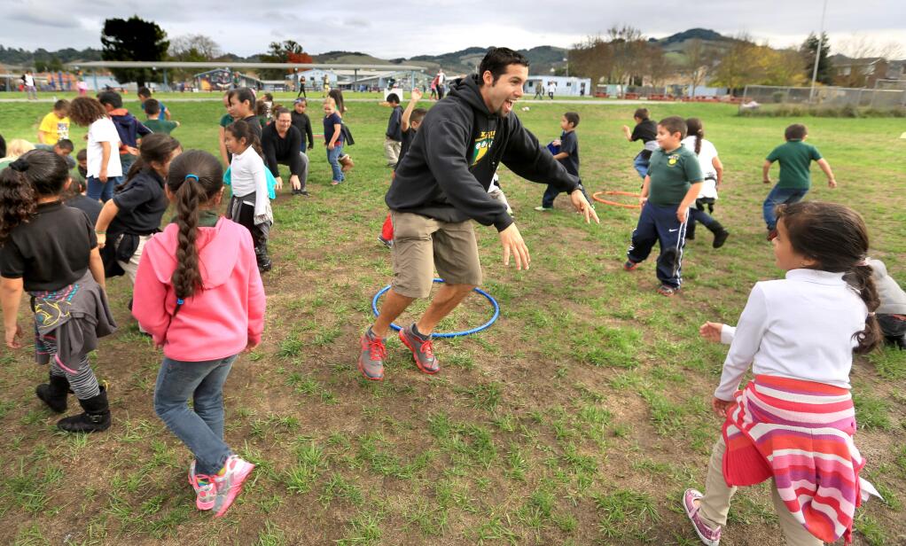 Bellvue School District PE instructor Luis Patrick encourages his students to hop during a game of musical hula hoops, Monday Dec. 8, 2014 at Kawana Elementary School in Santa Rosa. (Kent Porter / Press Democrat) 2014