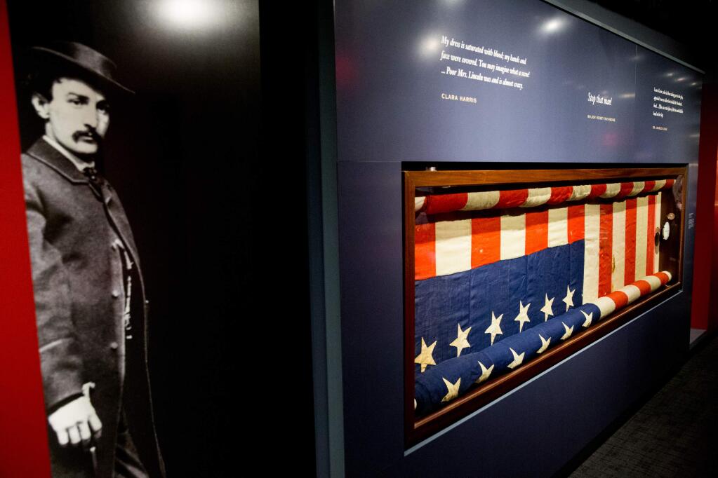 A photograph depicting President Abraham Lincoln's assassin, John Wilkes Booth, is displayed next to the bunting flag hung from the presidential box at Ford's Theatre at an exhibit in Washington. (ANDREW HARNIK / Associated Press)