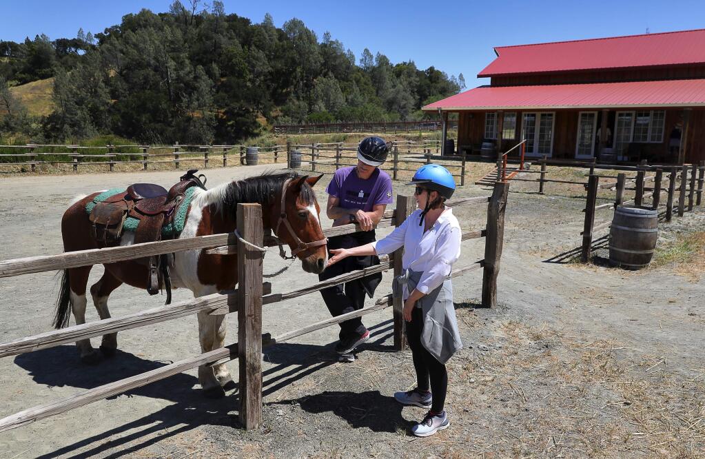 Mike and Terri Estes, visiting from Richmond, Virginia, pet one of the horses before going on a scenic ride at The Ranch at Lake Sonoma on Thursday, May 17, 2018. (Christopher Chung/ The Press Democrat)