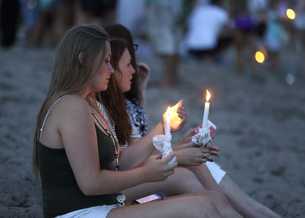 Julia Wolf, 16, left, and Jordan Harley, right, both of Stuart, Fla., hold candles during a vigil for Austin Stephanos and Perry Cohen, Tuesday, July 28, 2015, in Stuart, Fla. The two teenagers have been missing since last Friday when they went out on a boat to go fishing from Tequesta, Fla. A search continues for the boys from the Atlantic waters off Daytona Beach, Florida, north through Savannah, Ga. (AP Photo/Lynne Sladky)