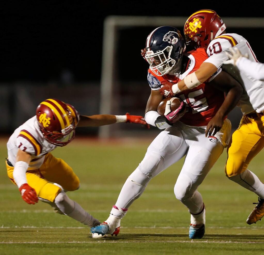 Rancho Cotate running back Rasheed Rankin (25), center, is tackled by Cardinal Newman's Zach Moran (10), right, and Jared Doolittle (11) during the first half of a varsity football game between Cardinal Newman and Rancho Cotate high schools, in Rohnert Park, California, on Friday, October 4, 2019. (Alvin Jornada / The Press Democrat)