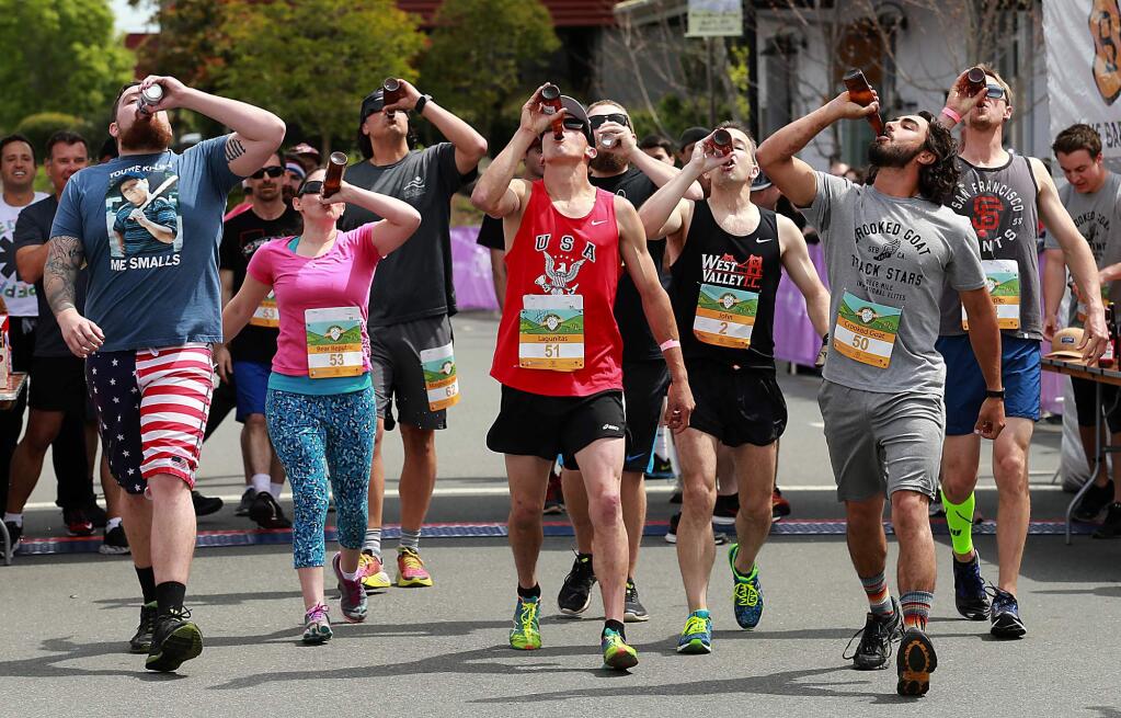 Competitors in the Beer Mile Invitational try to outrun and outdrink each other as they chugged a beer every quarter mile before dashing around The Barlow in Sebastopol on Saturday. (John Burgess/The Press Democrat)