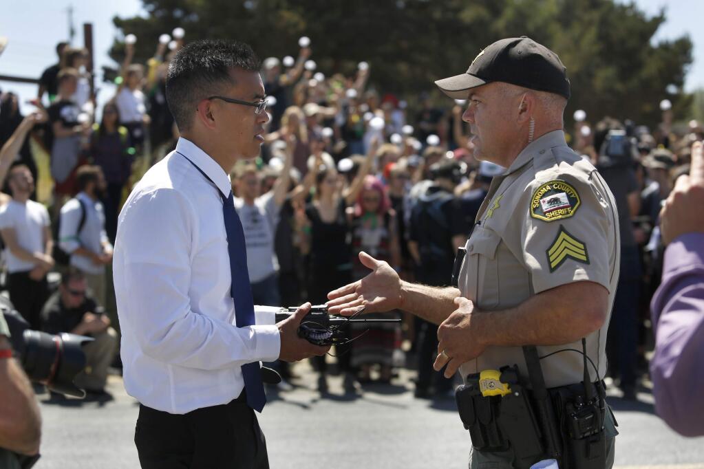 Wayne Hsiung, a lawyer and co-founder of Direct Action Everywhere, an animal rights network, talks with Sonoma County Sheriff's Sgt. Dave Thompson at a protest outside Weber Family Farms on Tuesday, May 29, 2018 in Petaluma, California . (BETH SCHLANKER/The Press Democrat)