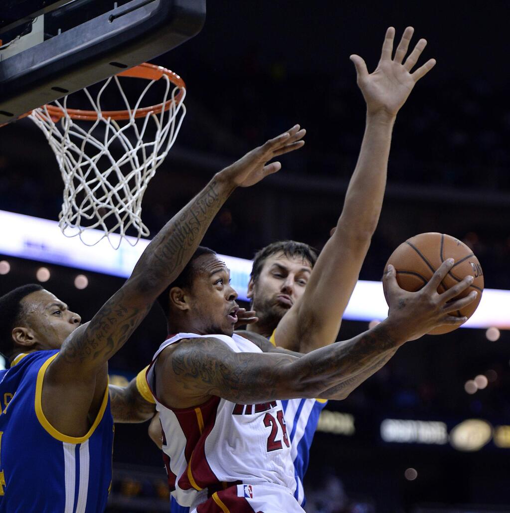 Miami Heat's Shannon Brown goes up for a no-look shot off over his head with Golden State Warriors' Brandon Rush, left, and Andrew Bogut defending during the first half of an NBA preseason basketball game Friday, Oct. 17, 2014, in Kansas City, Mo. (AP Photo/The Kansas City Star, Keith Myers)