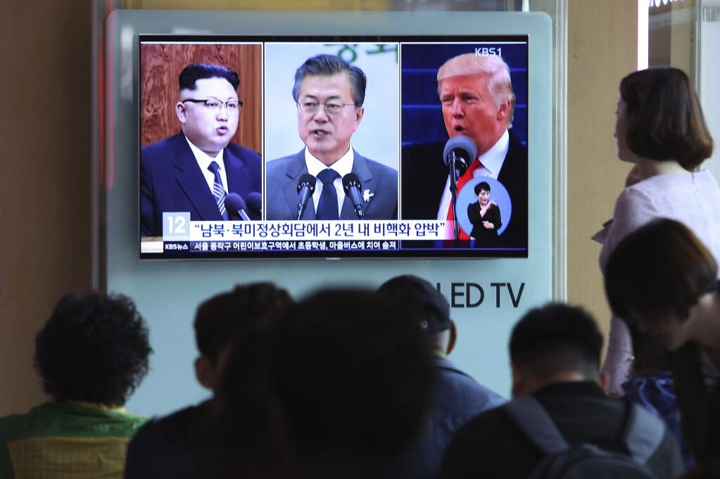 People watch a TV screen showing file footage of U.S. President Donald Trump, right, South Korean President Moon Jae-in and North Korean leader Kim Jong Un, left, during a news program at the Seoul Railway Station in Seoul, South Korea, Wednesday, April 18, 2018. Trump has given his 'blessing' for North and South Korea to discuss the end of the Korean War at their summit next week amid a diplomatic push to end the North Korean nuclear standoff. The signs read: ' Summit meeting between South and North Korea, the United States and North Korea .' (AP Photo/Ahn Young-joon)