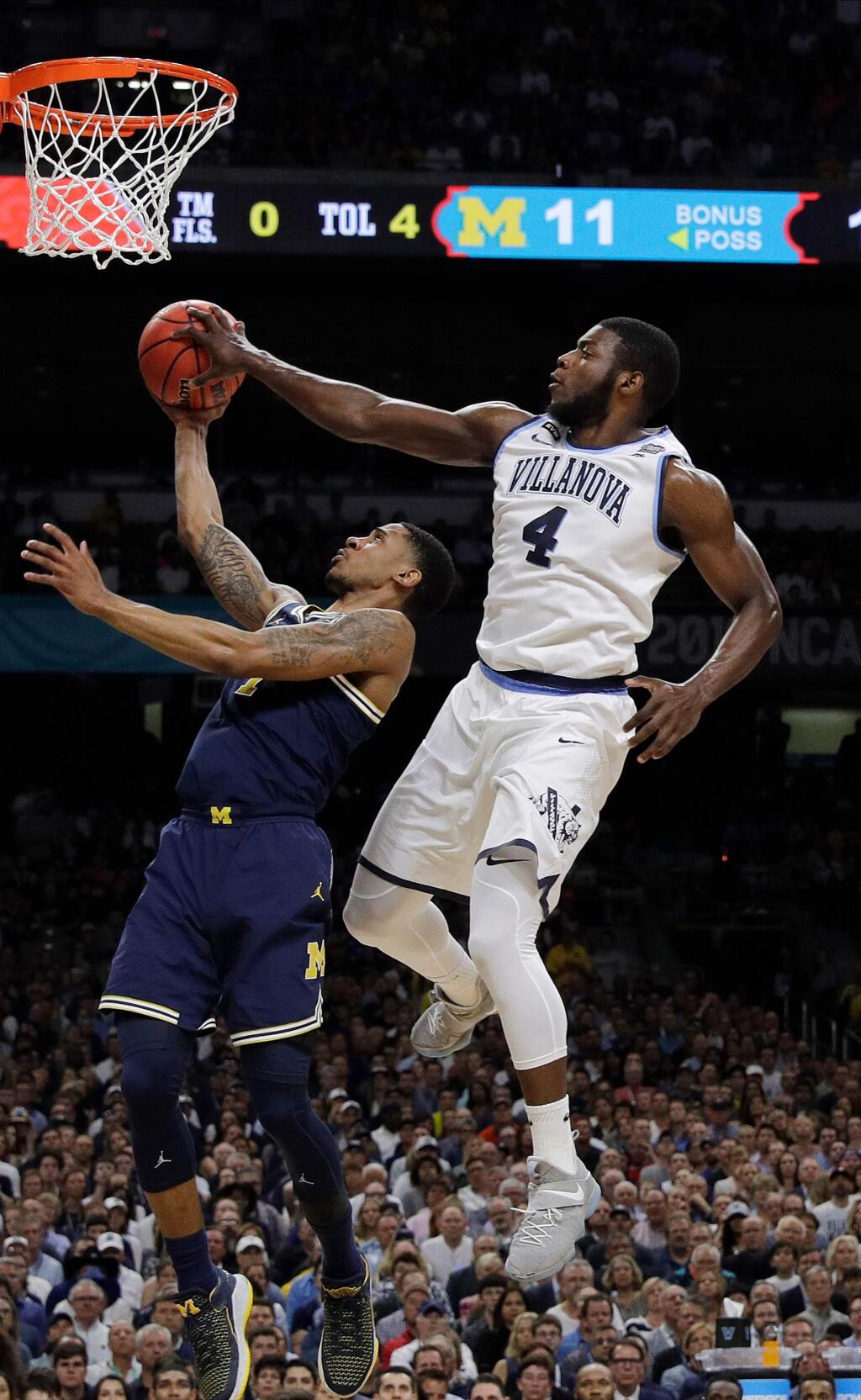 Villanova's Eric Paschall (4) blocks a shot by Michigan's Charles Matthews (1) during the first half in the championship game of the Final Four NCAA college basketball tournament, Monday, April 2, 2018, in San Antonio. (AP Photo/David J. Phillip)