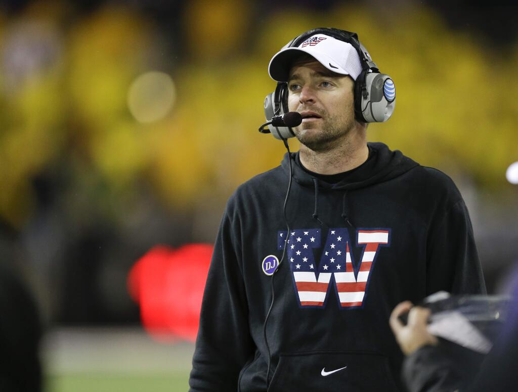 Washington defensive coordinator Justin Wilcox wears a sweatshirt and cap with a special team logo to honor veterans as he coaches against Colorado Saturday, Nov. 9, 2013, in Seattle. (AP Photo/Ted S. Warren)