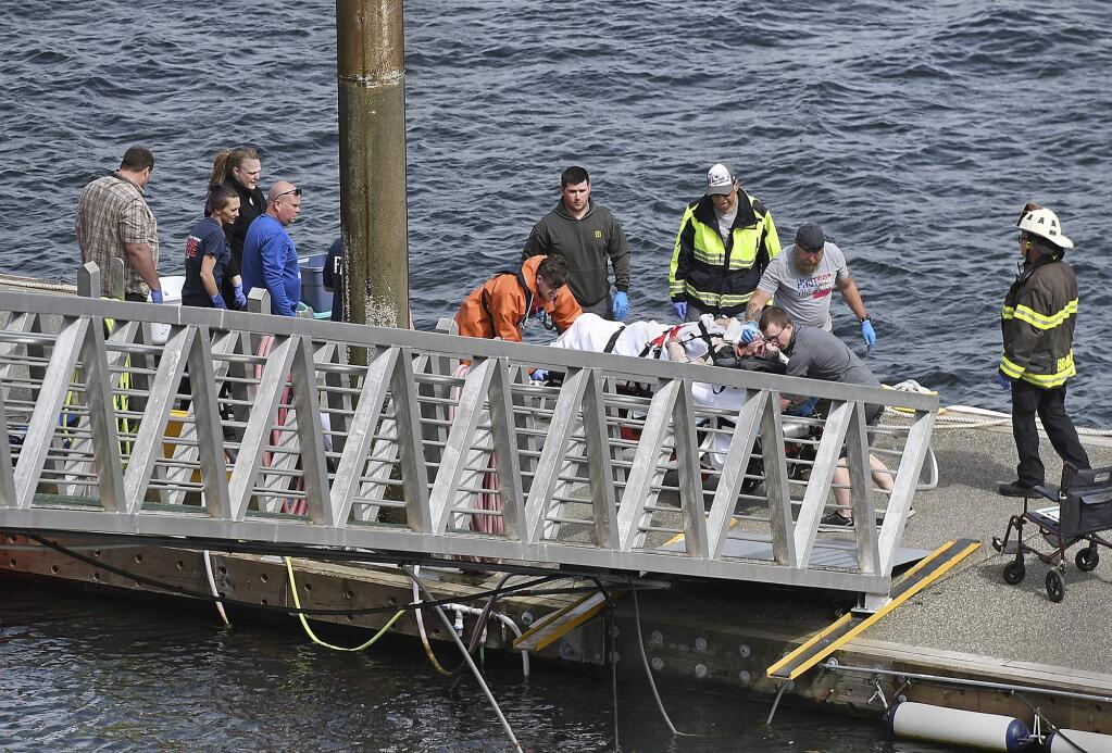 Emergency response crews transport an injured passenger to an ambulance at the George Inlet Lodge docks, Monday, May 13, 2019, in Ketchikan, Alaska. The passenger was from one of two float planes reported down in George Inlet early Monday afternoon and was dropped off by a U.S. Coast Guard 45-foot response boat. (Dustin Safranek/Ketchikan Daily News via AP)