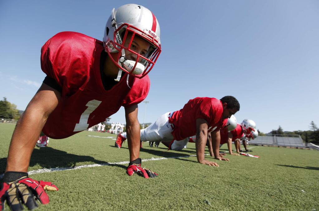 The Montgomery High School football Ke' Shawn Walker, left, does a plank with his teammates during the first day of practice, Monday, August 11, 2014. (Crista Jeremiason / The Press Democrat)