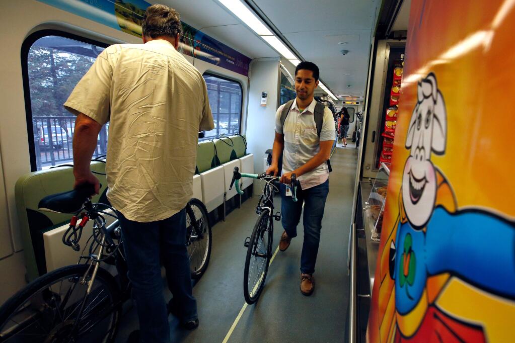 SMART train commuter Treebel Solimani, right, pushes his bicycle toward the exit as the train nears the station in Rohnert Park, California, on Wednesday, September 20, 2017. (Alvin Jornada / The Press Democrat)