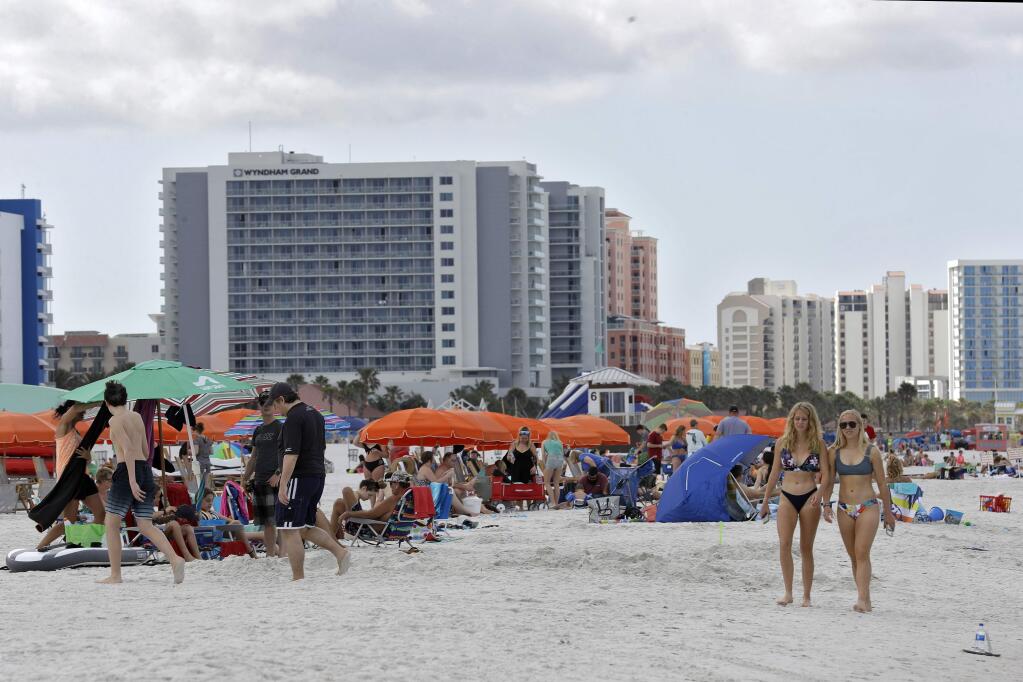 Visitors enjoy North Beach Tuesday, March 17, 2020, in Clearwater Beach, Fla. Beach goers are keeping a safe distance to avoid the spread of the coronavirus as they enjoy the Florida weather. (AP Photo/Chris O'Meara)