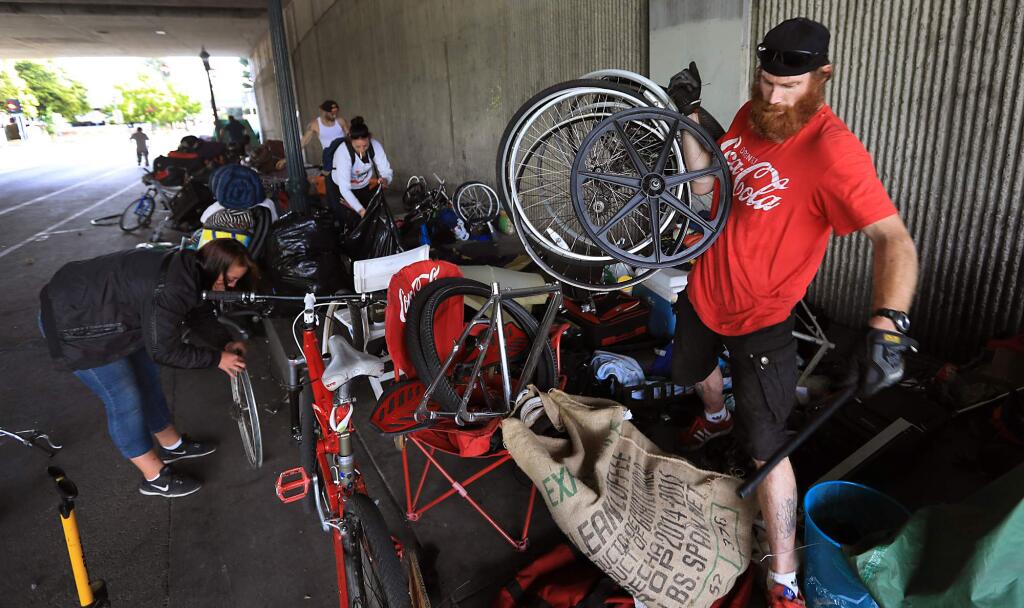 Bicycle Dave collects his belongings as he and others clean up their homeless campsites at the Sixth Street underpass in Santa Rosa prior to city crews washing down the sidewalk and collecting trash, Wednesday Sept. 20, 2017. (Kent Porter / The Press Democrat) 2017