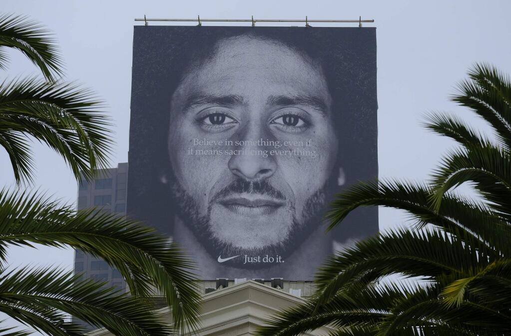 Palm trees frame a large billboard on top of a Nike store that shows former San Francisco 49ers quarterback Colin Kaepernick at Union Square, Wednesday, Sept. 5, 2018, in San Francisco. An endorsement deal between Nike and Colin Kaepernick prompted a flood of debate Tuesday as sports fans reacted to the apparel giant backing an athlete known mainly for starting a wave of protests among NFL players of police brutality, racial inequality and other social issues. (AP Photo/Eric Risberg)