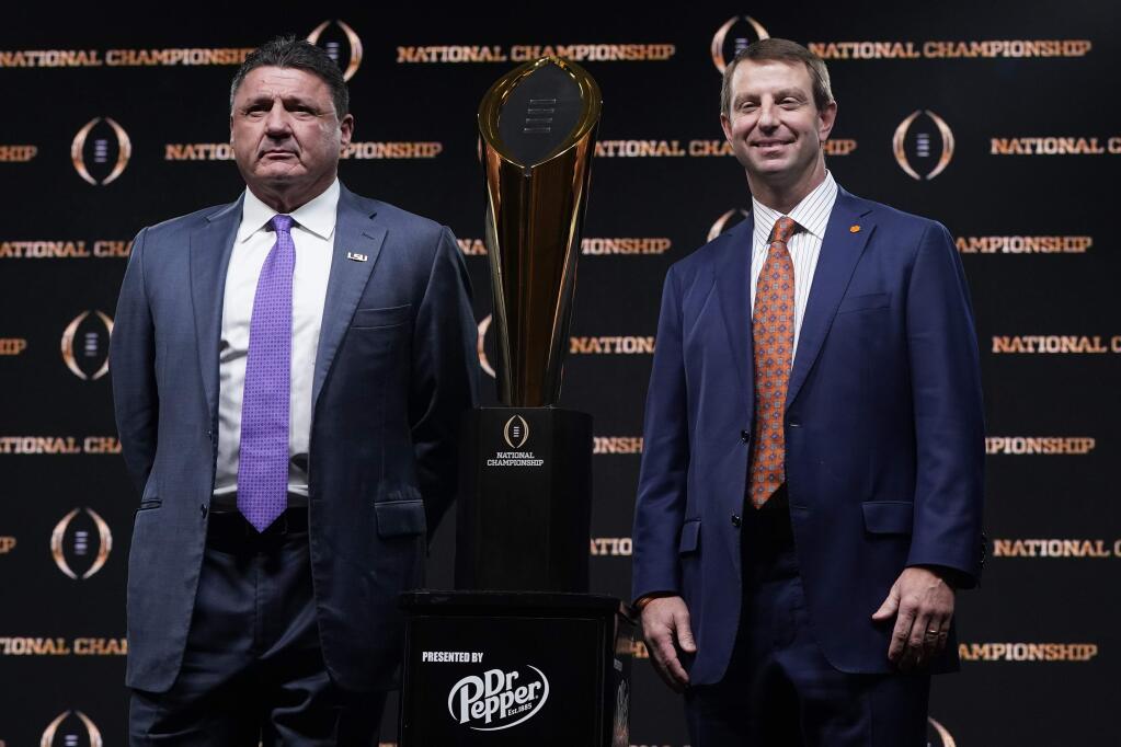 LSU head coach Ed Orgeron, left, and Clemson head coach Dabo Swinney pose with the trophy after a news conference for the NCAA College Football Playoff national championship game Sunday, Jan. 12, 2020, in New Orleans. Clemson is scheduled to play LSU on Monday. (AP Photo/David J. Phillip)