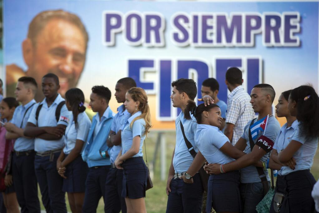 Students wait to see the ashes of Cuba's leader Fidel Castro driven to the Santa Ifigenia cemetery in Santiago, Cuba, Sunday, Dec. 4, 2016. The motorcade carrying the ashes made i's final journey towards the cemetery as thousands of people lined the short route from the Plaza Antonio Maceo.(AP Photo/Ricardo Mazalan)