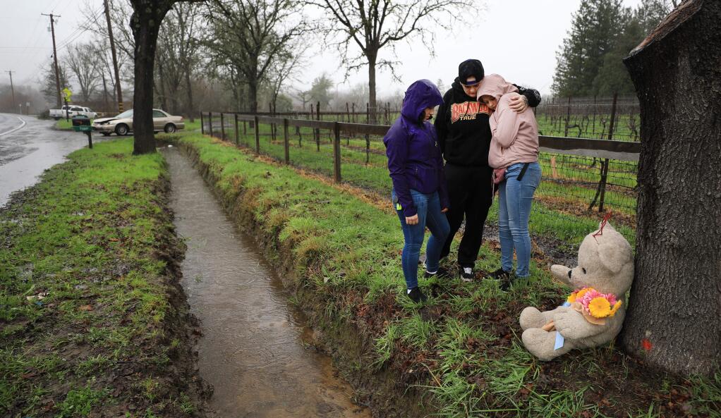 Natalia Lepore, middle, the girlfriend of Mallory Parker, who died Monday in a car crash on Occidental road, left, comforts her friends Alazay Nelson, left, and Jamie Pollard, Tuesday Jan. 15, 2019 at the crash site west of Highway 116 as they mourn their friend by placing a stuffed bear and flowers. (Kent Porter / Press Democrat) 2019