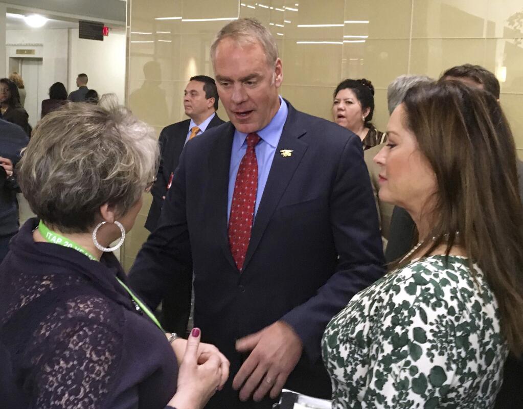 FILE - In this March 3, 2017, file photo, newly sworn-in Interior Secretary Ryan Zinke, with his wife Lola, right, greets an Interior Department employee on the Interior Department's 168th birthday at the Interior Department in Washington. Documents obtained by a left-leaning group show that Zinke's wife played a key role in arranging aspects of her husband's official events and often accompanied him on trips outside of Washington D.C. during the first few months of the administration. (AP Photo/Matthew Daly, File)