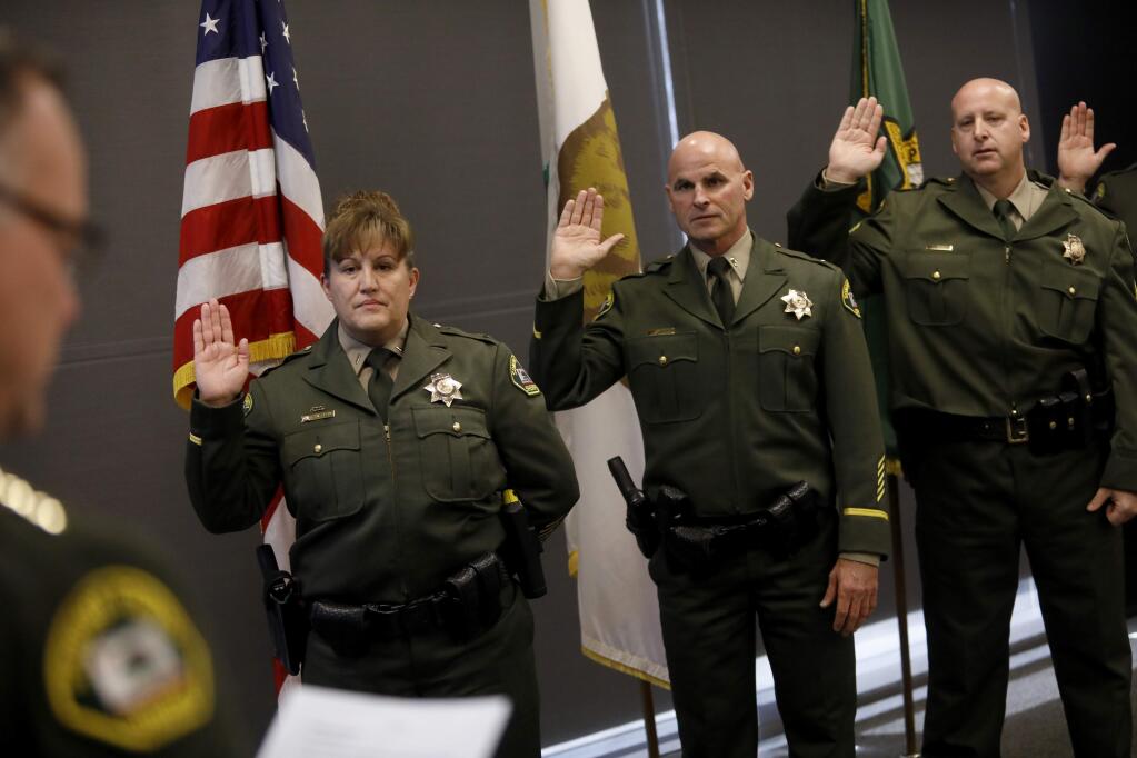 Sheriff Mark Essick, far left, swears in Andrea Salas as Lieutenant, Michael Raasch as Lieutenant, Eric Salkin as Sergeant, and Brent Kidder (not seen) as Sergeant, during a ceremony at the Sonoma County Sheriff's Office on Thursday, January 24, 2019 in Santa Rosa, California . (BETH SCHLANKER/The Press Democrat)