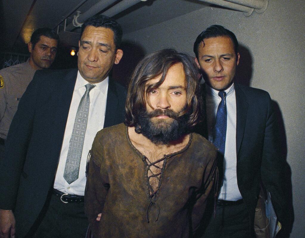 FILE - In this 1969 file photo, Charles Manson is escorted to his arraignment on conspiracy-murder charges in connection with the Sharon Tate murder case. A Los Angeles judge on Friday, Jan. 26, 2018, will hear arguments on what county should decide who gets the remains of cult leader Manson who orchestrated the 1969 killings of pregnant actress Tate and eight others. Three camps with alleged ties to Manson, who died in Nov. 2017, claim they want to properly bury or dispose of Manson's ashes, though they allege others want to profit off the remains. (AP Photo, File)