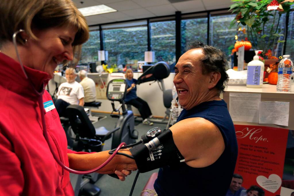 Vicente 'Rayo' Tlatilpa laughs with exercise physiologist Kathy Hutchinson as she measures his blood pressure before his rehab workout at HeartWorks in Santa Rosa, California on Wednesday, November 25, 2015. (Alvin Jornada / The Press Democrat)