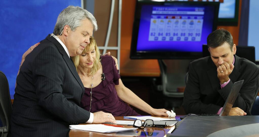 WDBJ-TV7 news morning anchor Kimberly McBroom, center, gets a hug from visiting anchor Steve Grant, left, as meteorologist Leo Hirsbrunner reflects after their early morning newscast at the station, Thursday, Aug. 27, 2015, in Roanoke, Va. Reporter Alison Parker and cameraman Adam Ward were killed during a live broadcast Wednesday, while on assignment in Moneta. (AP Photo/Steve Helber)