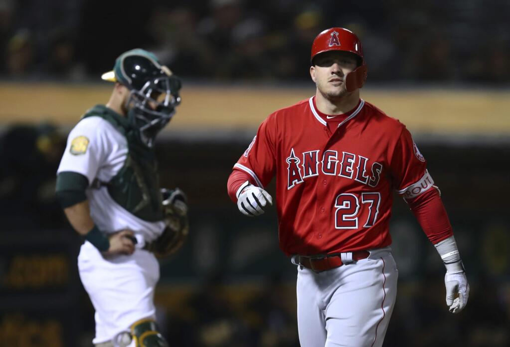 The Los Angeles Angels' Mike Trout, right, crosses home plate after hitting a home run off the Oakland Athletics' Daniel Mengden during the fourth inning Tuesday, Sept. 18, 2018, in Oakland. (AP Photo/Ben Margot)