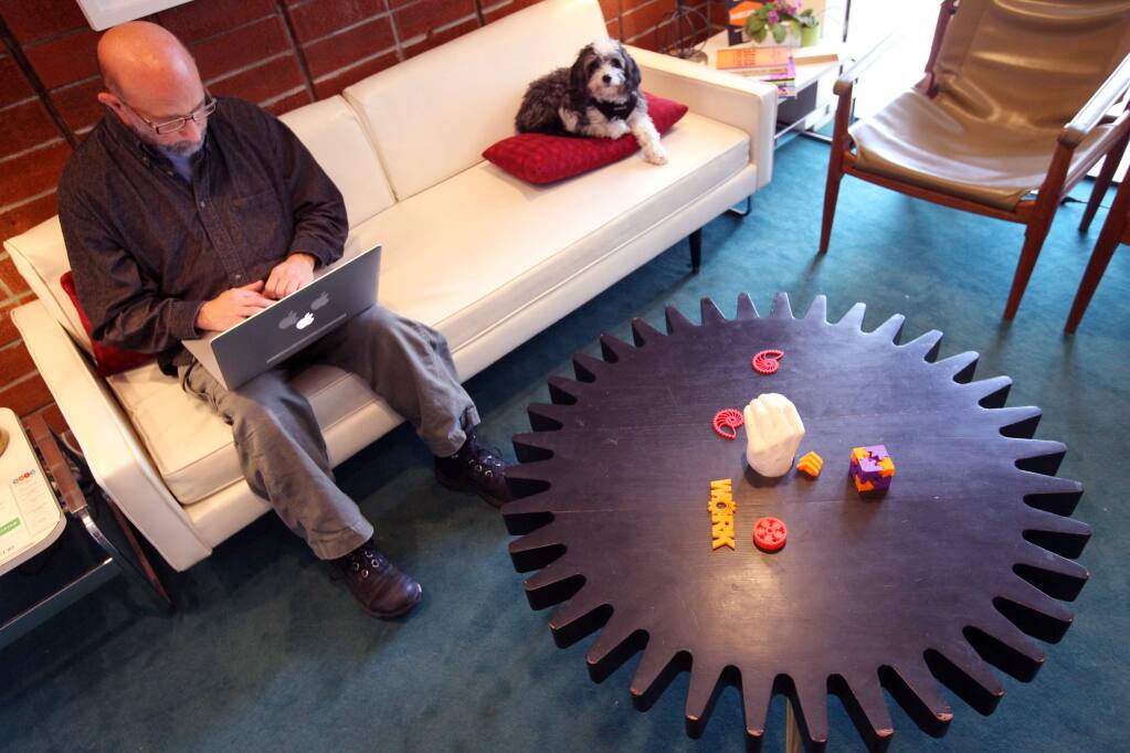 Jeffrey Ventrella, founder of Wiggle Planet works at a couch beside his dog Otto at co-working office space WORK in Petaluma, California on Thursday, December 10, 2015. (Alvin Jornada / The Press Democrat)