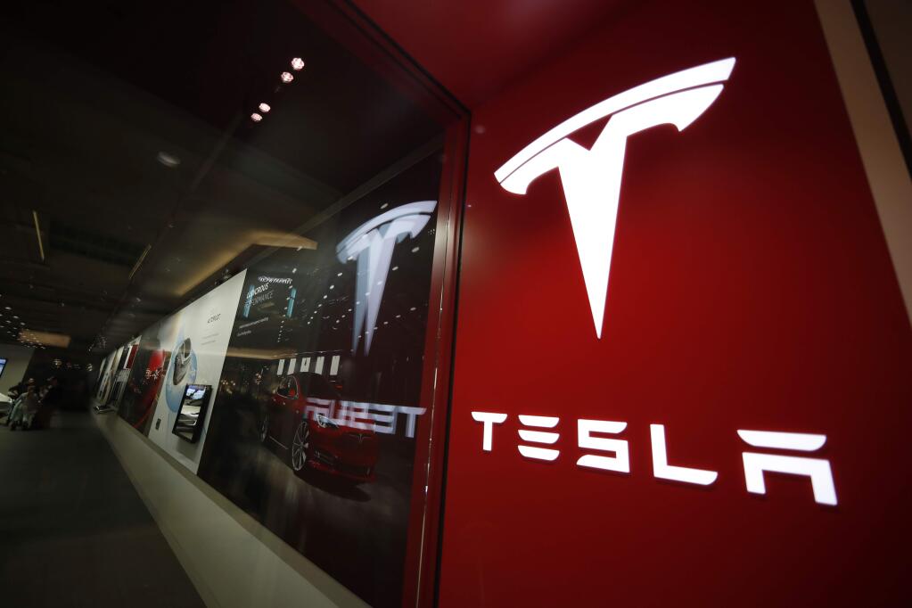 FILE- In this Feb. 9, 2019, file photo, a sign bearing the company logo is displayed outside a Tesla store in Cherry Creek Mall in Denver. (AP Photo/David Zalubowski, File)