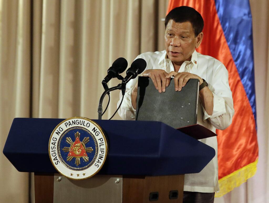 Philippine President Rodrigo Duterte holds documents containing a list of suspected drug dealers and users during the 19th Founding Anniversary of the Volunteers Against Crime and Corruption at the Malacanang Presidential Palace in Manila, Philippines on Wednesday, Aug. 16, 2017. (AP Photo/Aaron Favila)