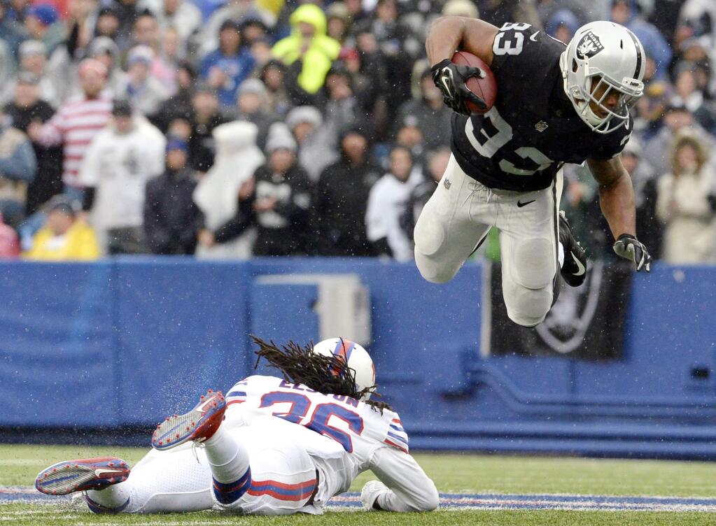 As rain falls, Oakland Raiders running back DeAndre Washington, right, goes airborne after being hit by Buffalo Bills defensive back Trae Elston during the first half Sunday, Oct. 29, 2017, in Orchard Park, N.Y. (AP Photo/Adrian Kraus)