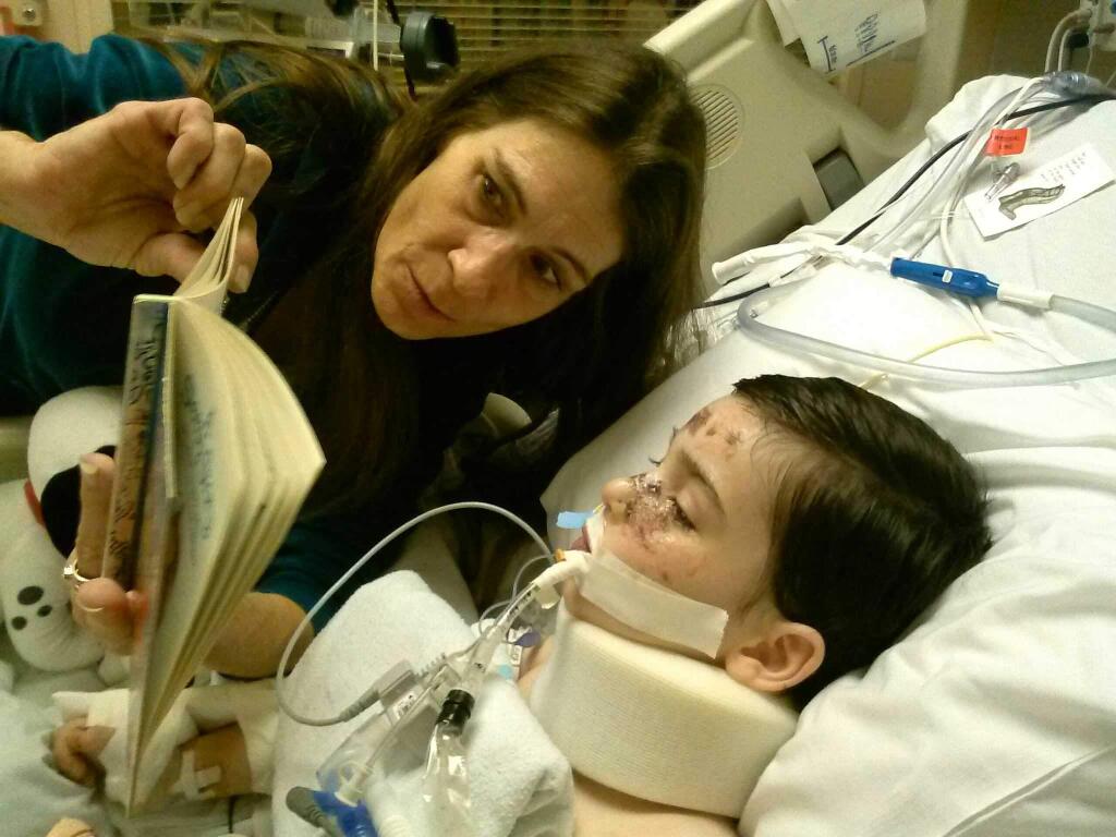 Leisa Davidson reads a story to her grandson Sebastion Johnson at Childrens Hospital Oakland as he continues to recover from a fall off a Bodega Head cliff earlier this month. (COURTESY PHOTO)