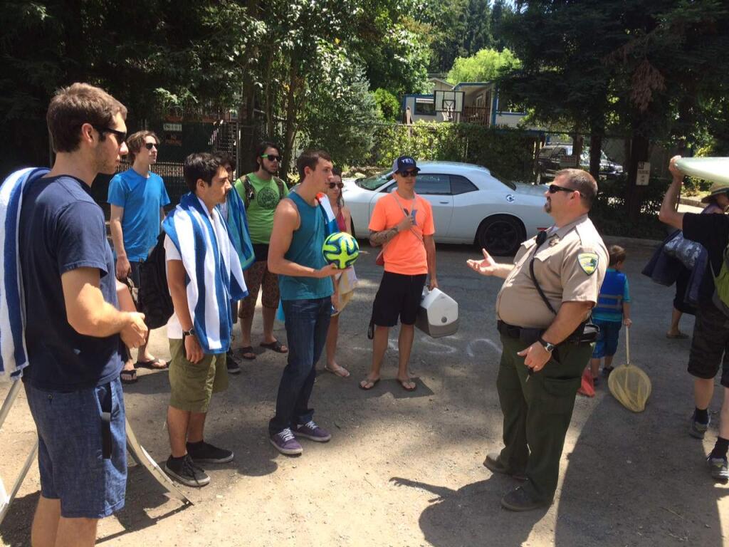 Sonoma County Ranger Scott Bolin talks to people at the entrance of Mom's Beach in Forestville on the Russian River about a new ban on alcohol, resulting in them returning to their car with their coolers, Wednesday, July 1, 2015. (JOHN BURGESS / PRESS DEMOCRAT)