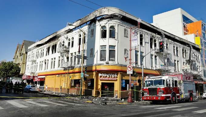 Firemen investigate the scene of a fatal fire Thursday, Jan. 29, 2015, in San Francisco. Officials are investigating whether fire alarms and fire escapes were working properly after a massive blaze ripped through a building in San Francisco's bustling Mission District, killing a man and injuring five other people. (AP Photo/Ben Margot)