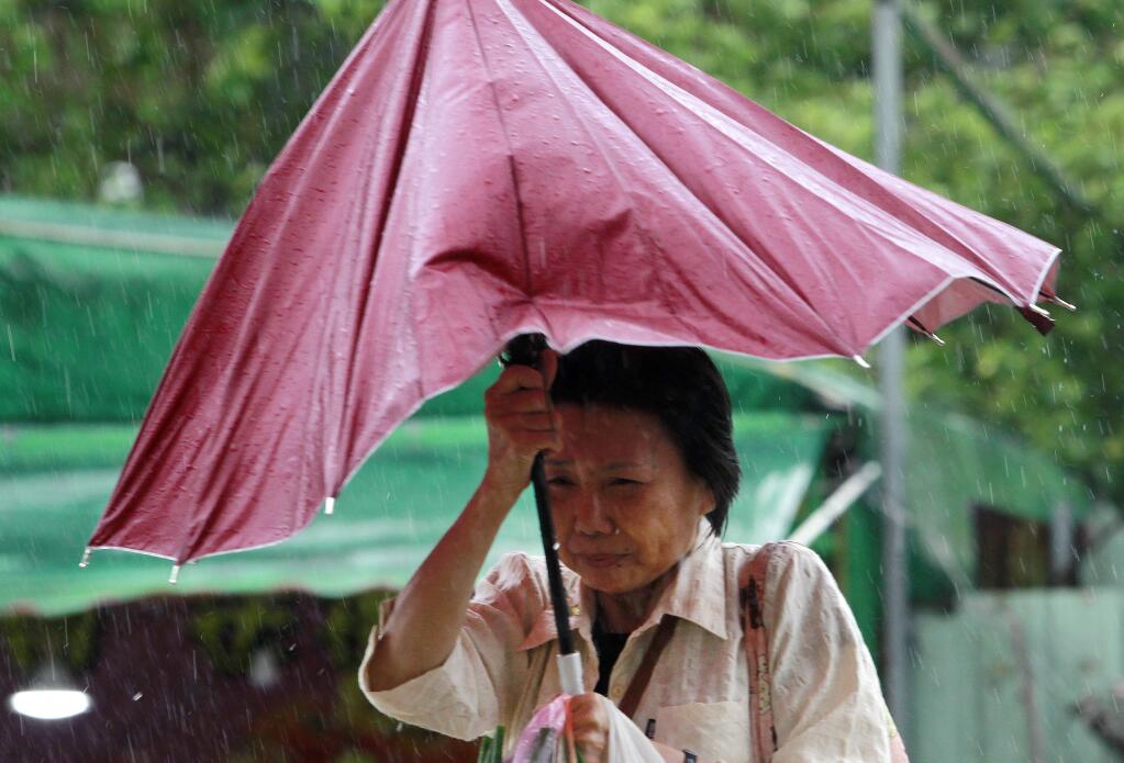 A woman struggles with her umbrella against powerful gusts of wind generated by typhoon Megi across the the island in Taipei, Taiwan, Tuesday, Sept. 27, 2016. (AP Photo/Chiang Ying-ying)