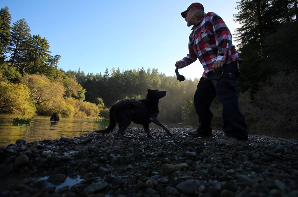 Gary Lukas, of Point Arena, tosses a stick for his dog, Jake, at the Gualala River, along Gualala River Road, on Monday, November 24, 2014.(Christopher Chung/ The Press Democrat)
