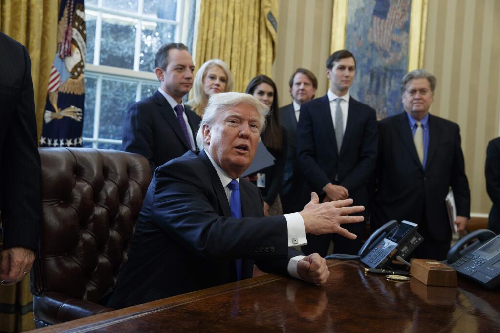 President Donald Trump talks with reporters in the Oval Office of the White House in Washington, Tuesday, Jan. 24, 2017. (AP Photo/Evan Vucci)