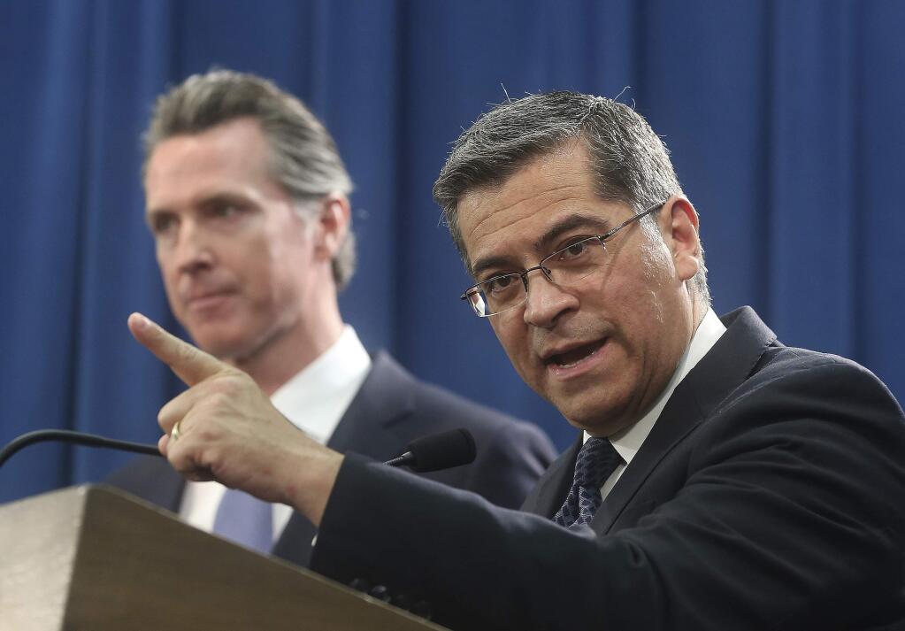 FILE - In this Feb. 15, 2019, file photo, California Attorney General Xavier Becerra, right, accompanied by Gov. Gavin Newsom, said California was probably suing President Donald Trump over his emergency declaration to fund a wall on the U.S.-Mexico border in Sacramento, Calif. Becerra filed a lawsuit Monday, Feb. 18, against Trump's emergency declaration to fund a wall on the U.S.-Mexico border. Becerra released a statement Monday, saying 16 states - including California - allege the Trump administration's action violates the Constitution. (AP Photo/Rich Pedroncelli, File)