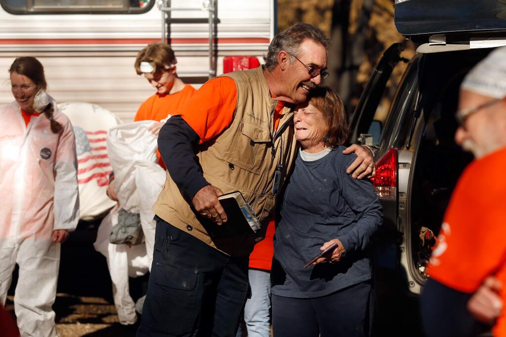 Camp Fire survivor Janet Clark, right, embraces David Elliott, a team leader with Samaritan's Purse relief organization after a group of Samaritan's Purse volunteers helped salvage what they could from the ashes of Clark's Tara Lane home that burned down during the Camp Fire, in Paradise, California, on Wednesday, December 12, 2018. (Alvin Jornada / The Press Democrat)