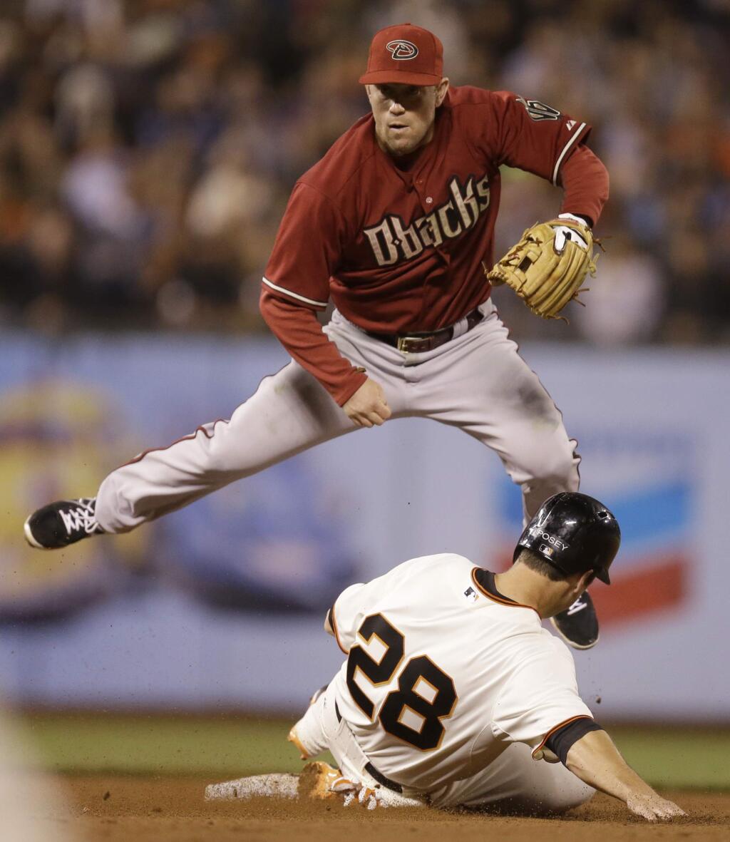Arizona Diamondbacks' Aaron Hill hops over San Francisco Giants' Buster Posey (28) after a throw to first base for a double play in the sixth inning of a baseball game Wednesday, Sept. 10, 2014, in San Francisco. Pablo Sandoval was out at first base. (AP Photo/Ben Margot)