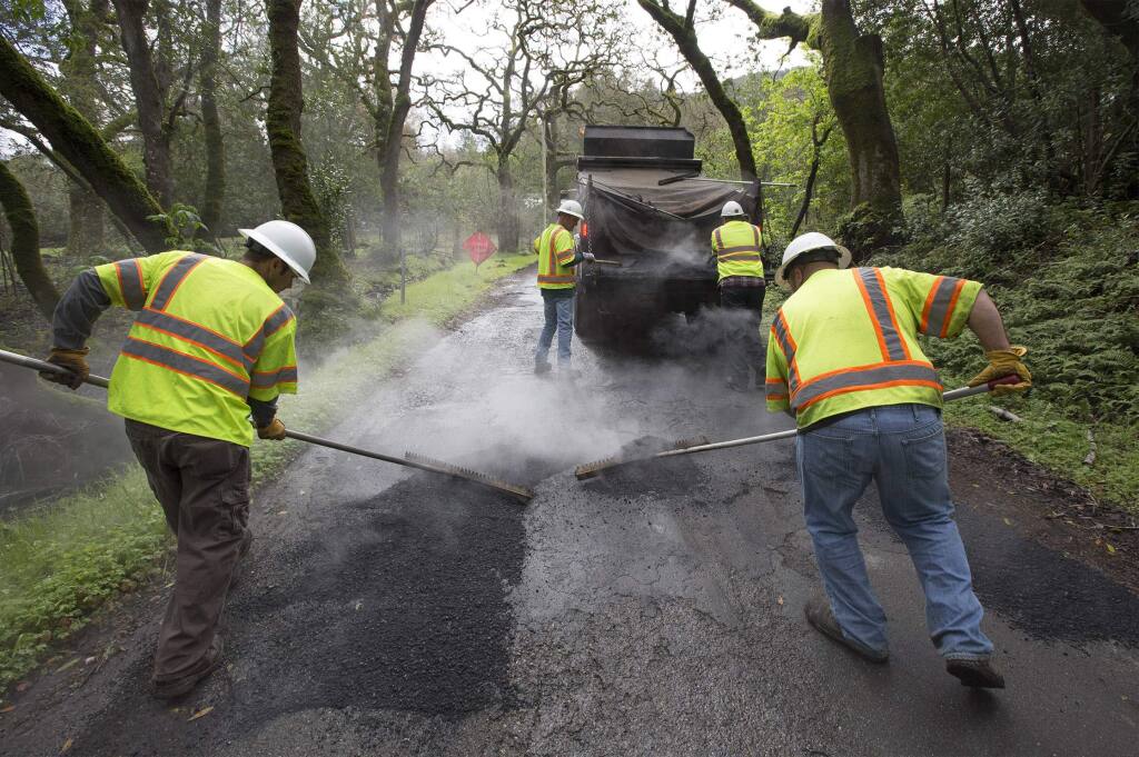 A county crew fills potholes on Enterprise Road on Monday, March 6, 2017. (Photo by Robbi Pengelly/Index-Tribune)