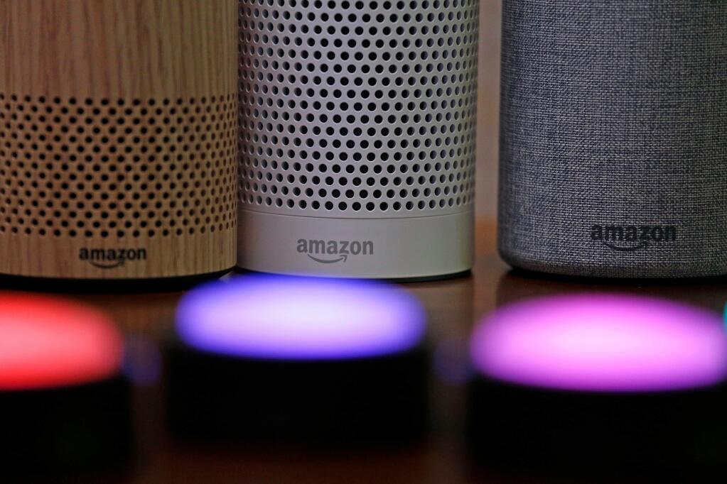 FILE - In this Sept. 27, 2017, file photo, Amazon Echo and Echo Plus devices, behind, sit near illuminated Echo Button devices during an event announcing several new Amazon products by the company in Seattle. The voice assistant that lives inside Amazon's Echo speakers will soon thank kids for shouting out questions “nicely” if they say “please.” The new response is part of a kid-friendly update that's coming next month, giving parents more control over the voice assistant.” (AP Photo/Elaine Thompson, File)